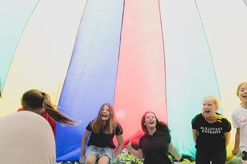 Girls laugh while playing with a parachute on the Circle
